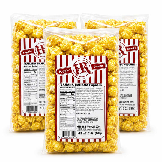 Three clear plastic bags of Poppin' Poppin' Banana-Banana Popcorn arranged in a triangular studio composition on a white background. The center bag is in front, showing the front label with red and white stripes, the brand logo, and product details.