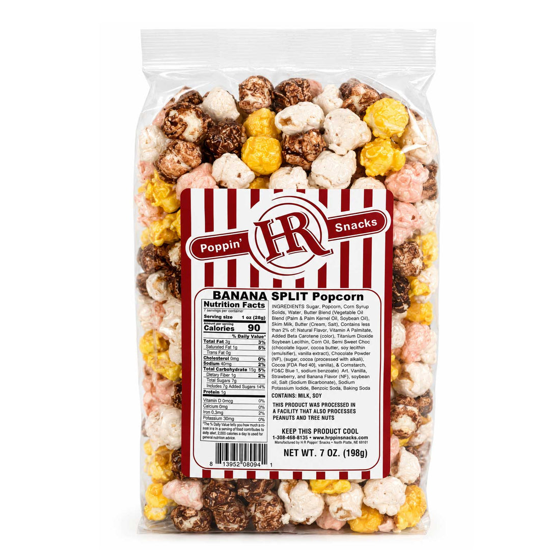 A 7 oz bag of Poppin' IR Snacks Banana Split Popcorn, featuring a clear plastic bag filled with a mix of white, yellow, pink, and brown popcorn pieces, complete with a red and white striped label.