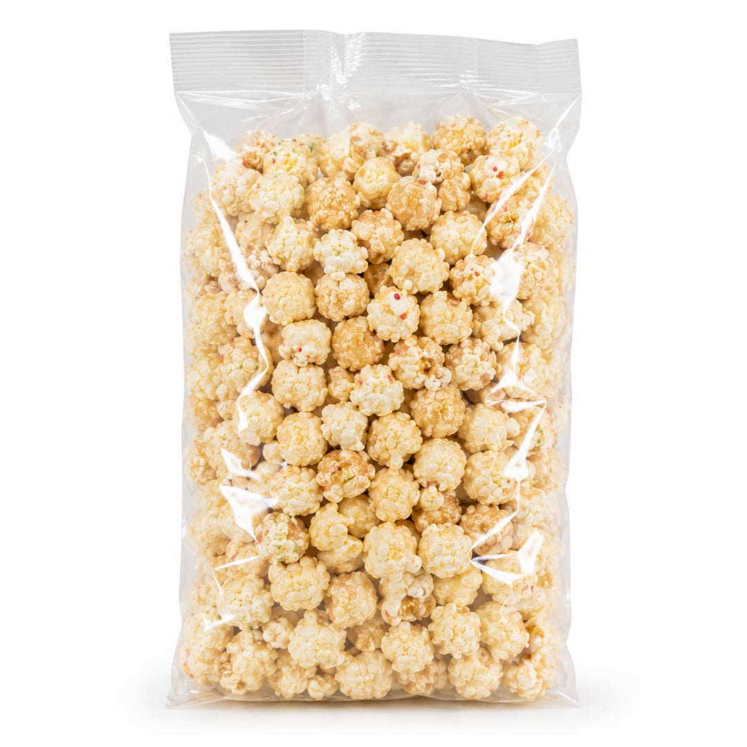 A clear plastic bag filled with lightly coated popcorn kernels, photographed upright on a clean white background.