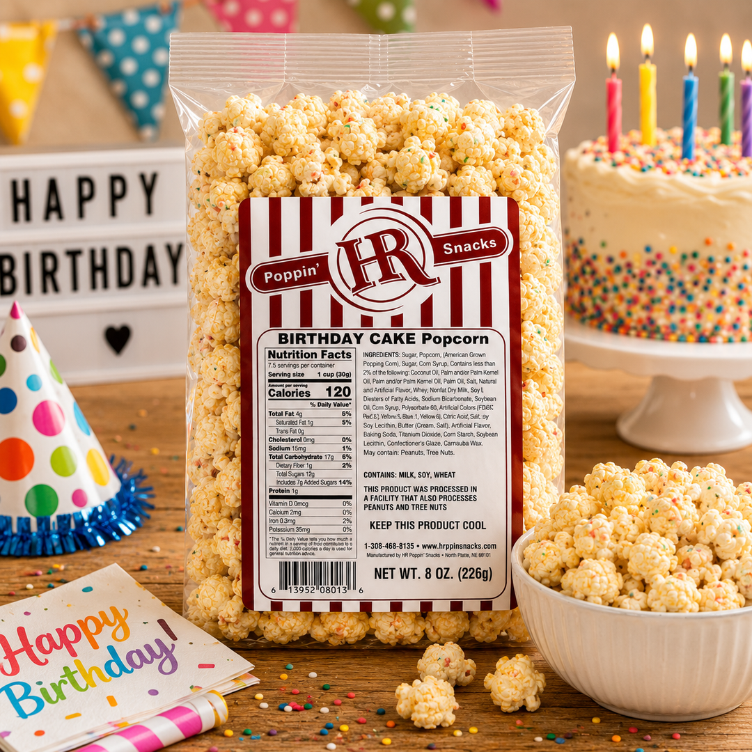 A 8 oz bag of Poppin' HR Snacks Birthday Cake Popcorn on a clean white background. The clear plastic bag shows the golden-yellow popcorn inside, with a prominent red and white striped label on the front.
