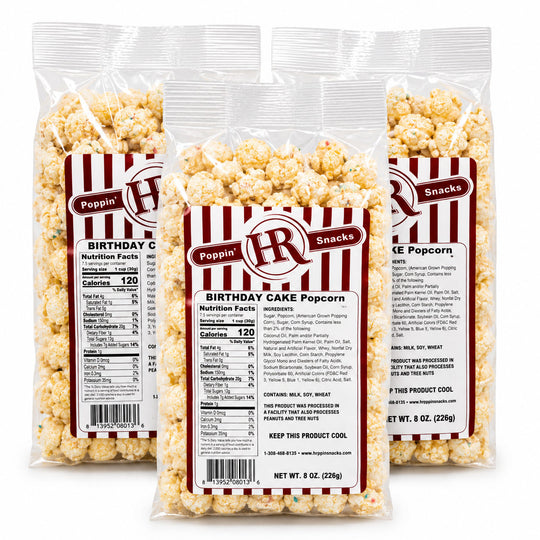 Three clear plastic bags of Poppin' Poppin' 'Birthday Cake' popcorn arranged in a fan shape against a white background, showing the front labels and the back nutrition panels.
