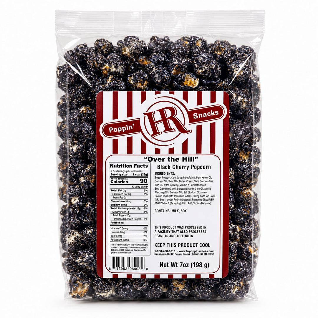 A 7 oz bag of Poppin' "Over the Hill" Black Cherry Popcorn on a clean white background. The clear plastic bag shows the dark, glossy popcorn inside, with a prominent red and white striped label on the front.