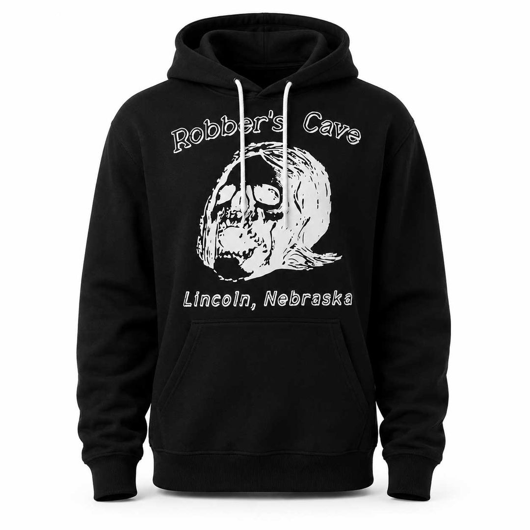 A black pullover hoodie with a white graphic print on the front. The design features a skull illustration with a revolver in its teeth, with the text 'Robber's Cave' above and 'Lincoln, Nebraska' below.