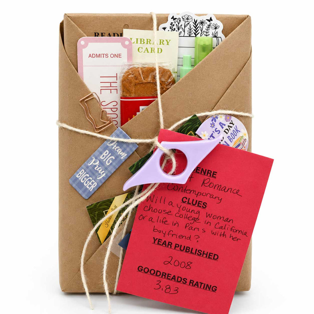 A brown kraft paper gift envelope wrapped with twine, filled with themed reading accessories and cards, photographed on a white background.