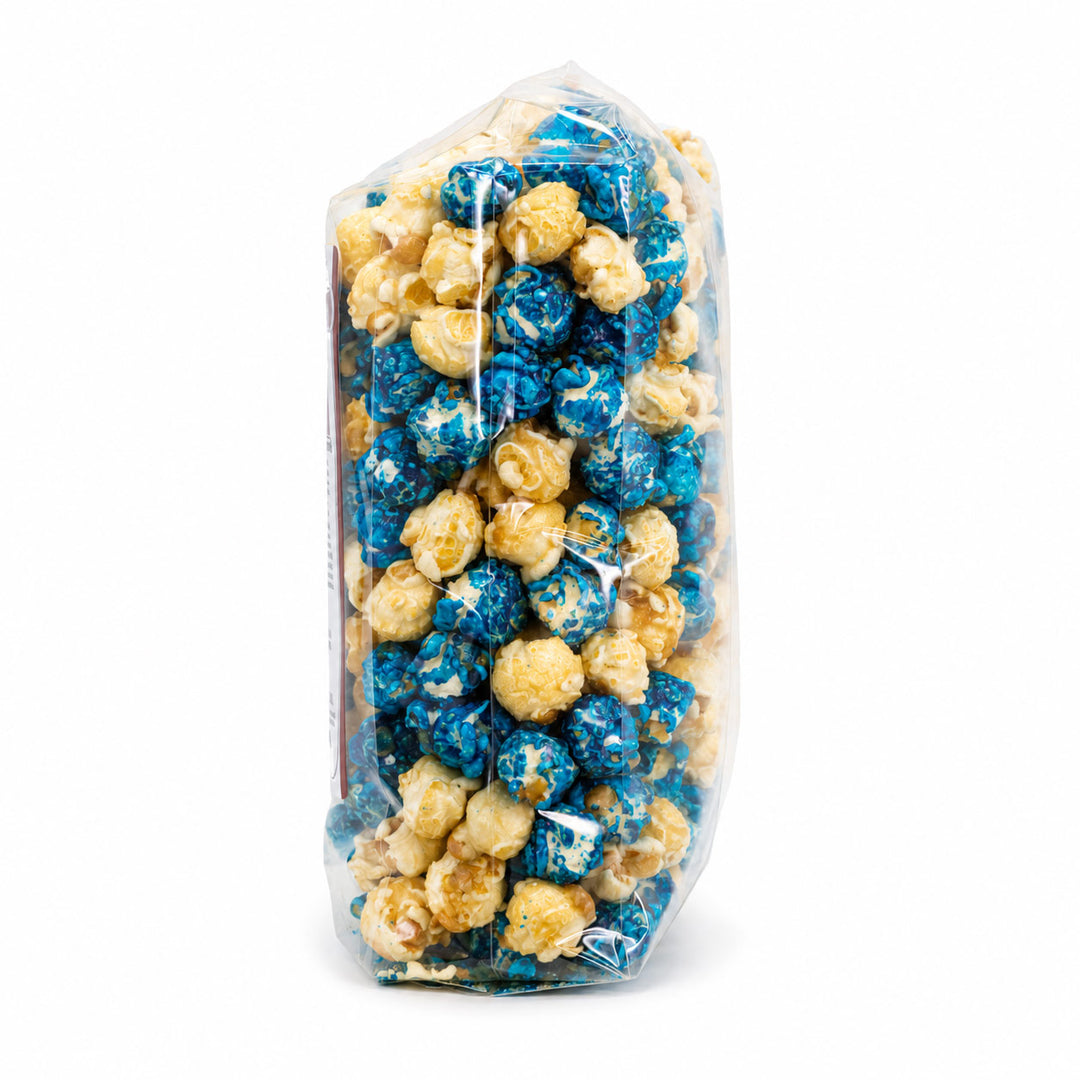 A clear plastic bag filled with popcorn, showing blue and tan popcorn kernels inside, isolated on a white background.