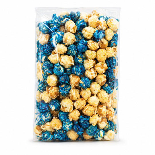 A clear plastic bag filled with mixed popcorn, including blue-coated popcorn and plain caramel popcorn, shown against a plain white background.