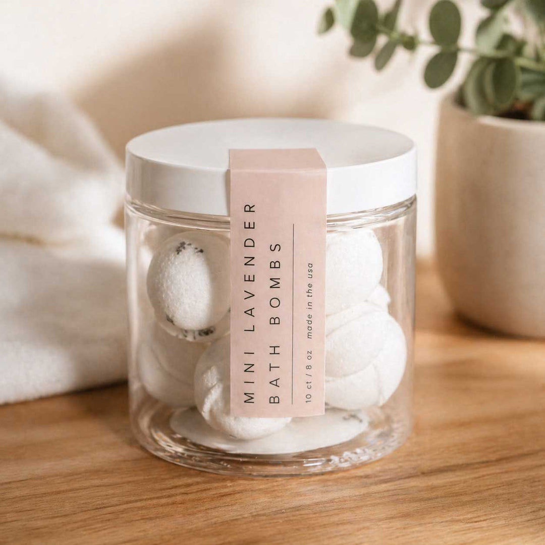 Jar of mini lavender bath bombs with a pink label on a wooden surface.