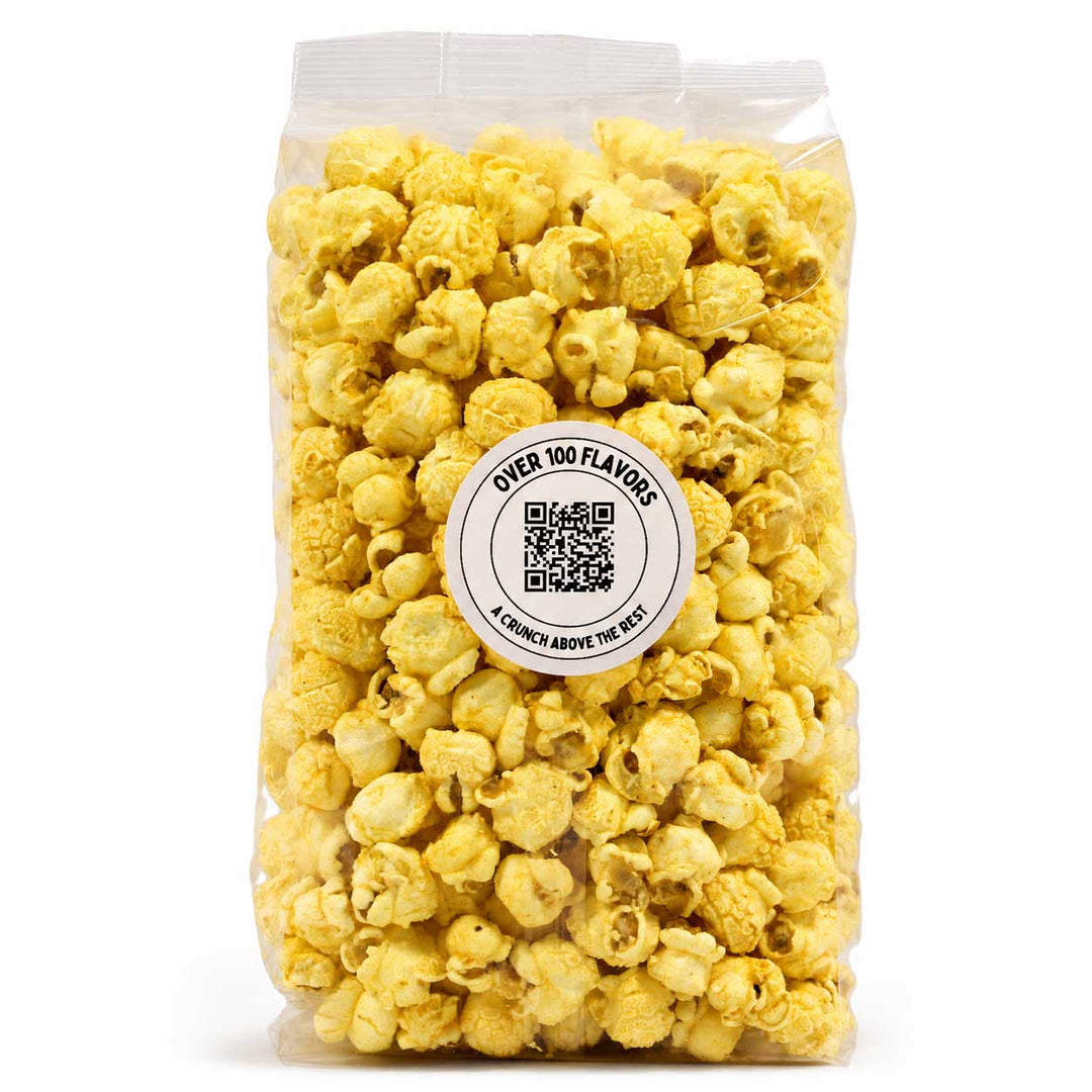 A clear plastic bag filled with yellow popcorn on a white background, featuring a round white label in the center that reads 'OVER 100 FLAVORS' with a QR code and the brand 'A Church Above The Facts'.