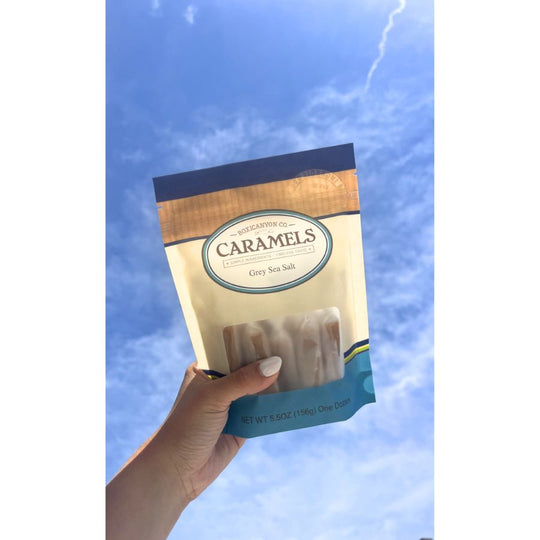 A bag of Grey Sea Salt Caramels getting held in the sky