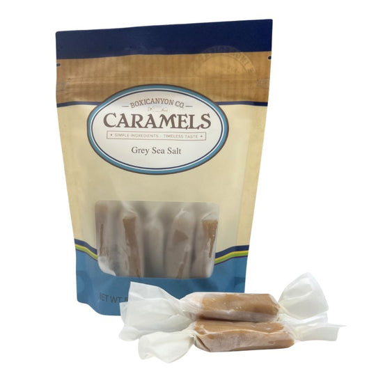 One bag of Grey Sea Salt Caramels with a small pile of individually wrapped caramels laying in front. 