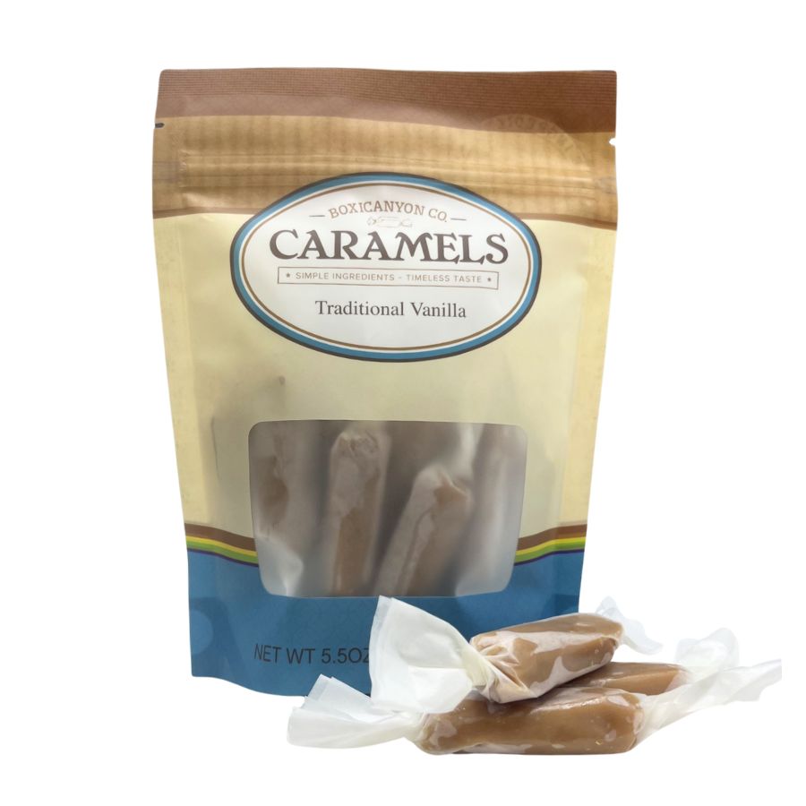 One package of Traditional Vanilla Caramels with a small pile of individually wrapped caramels laying in front of the package.