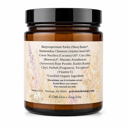 An amber glass jar with a black lid and a beige label featuring botanical illustrations, displaying product ingredients for Butyroserpum Parkii (Shea) Butter on a white background.