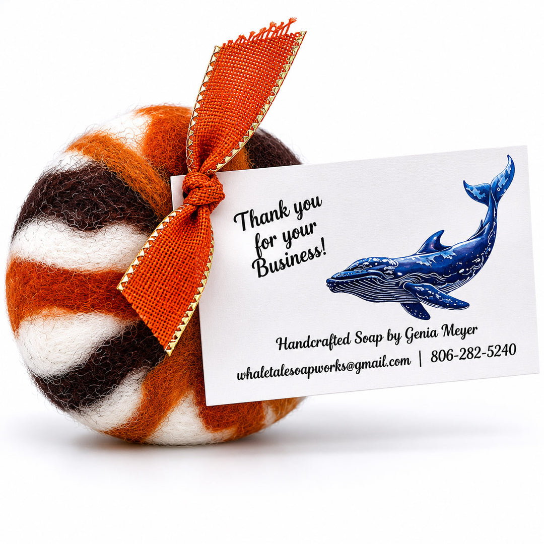 Handcrafted soap with a striped pattern and orange ribbon, featuring a business card with whale illustration.