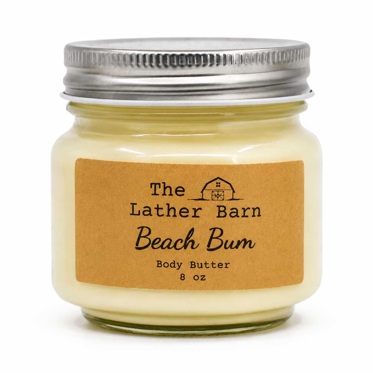 An 8 oz glass jar candle with creamy yellow wax, a kraft paper label reading 'The Lather Barn Beach Bum Body Butter', and a silver metal lid, shown on a white background.