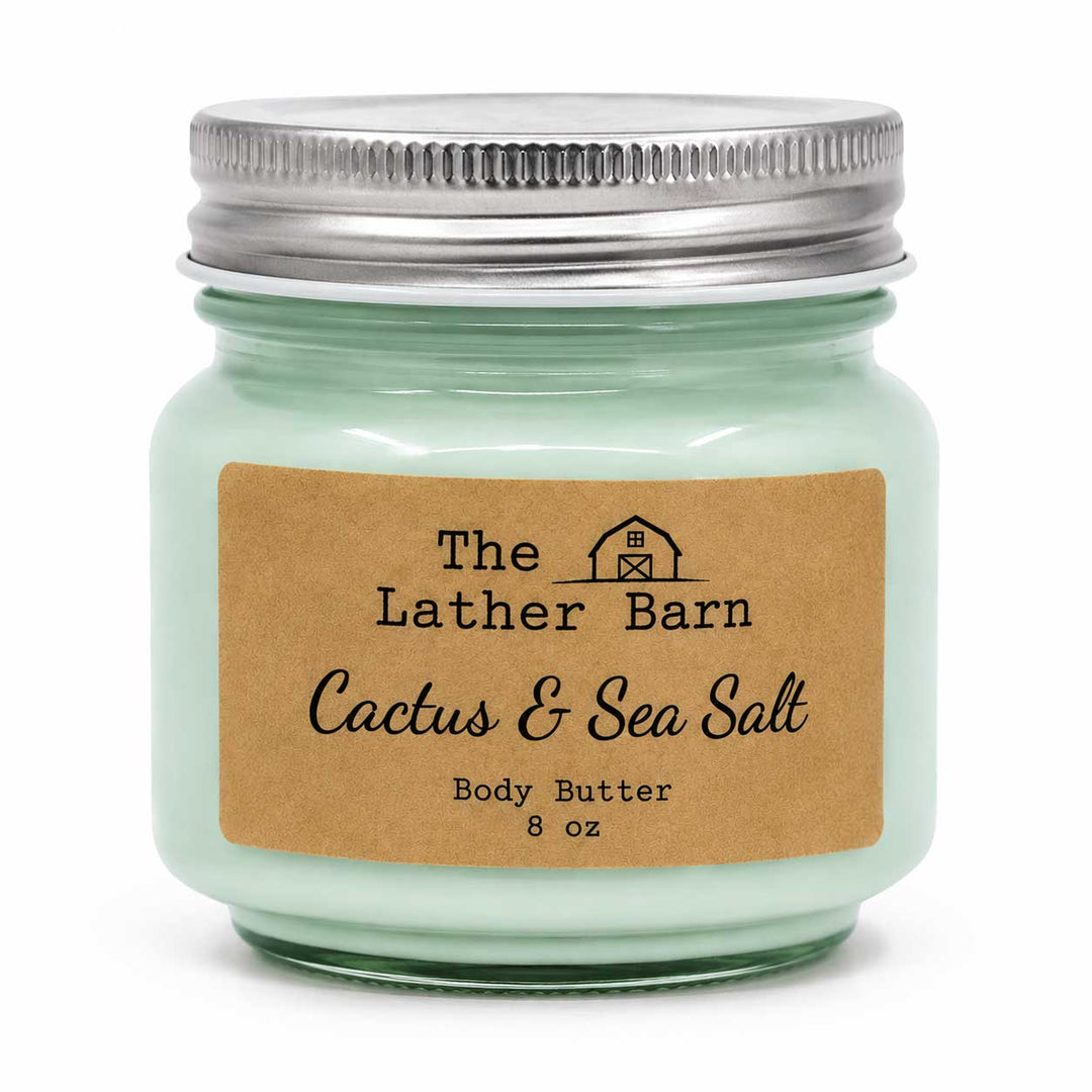 A mint green glass jar candle with a silver metal lid and a brown kraft paper label reading 'The Lather Barn Cactus & Sea Salt Body Butter 8 oz' on a white background.