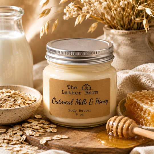 A jar of oatmeal milk and honey body butter by The Lather Barn, styled with oats, a honeycomb, a honey dipper, and a bottle of milk on a warm rustic background.