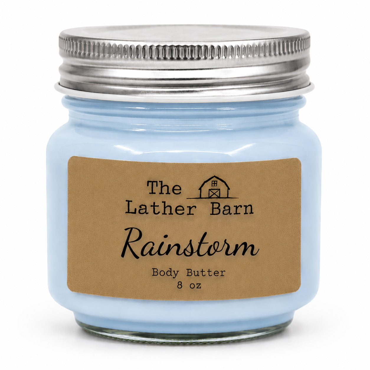 A light blue glass jar candle with a silver metal lid and a brown kraft paper label reading 'The Lather Barn Rainstorm Body Butter 8 oz' on a white background.