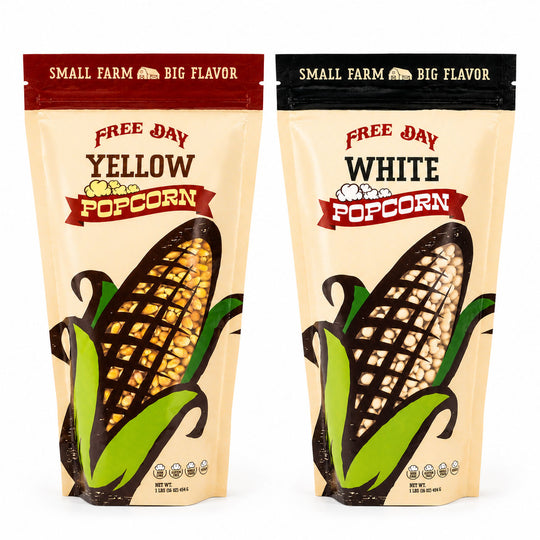 Two packages of Free Day Popcorn, one yellow and one white, on a white background.