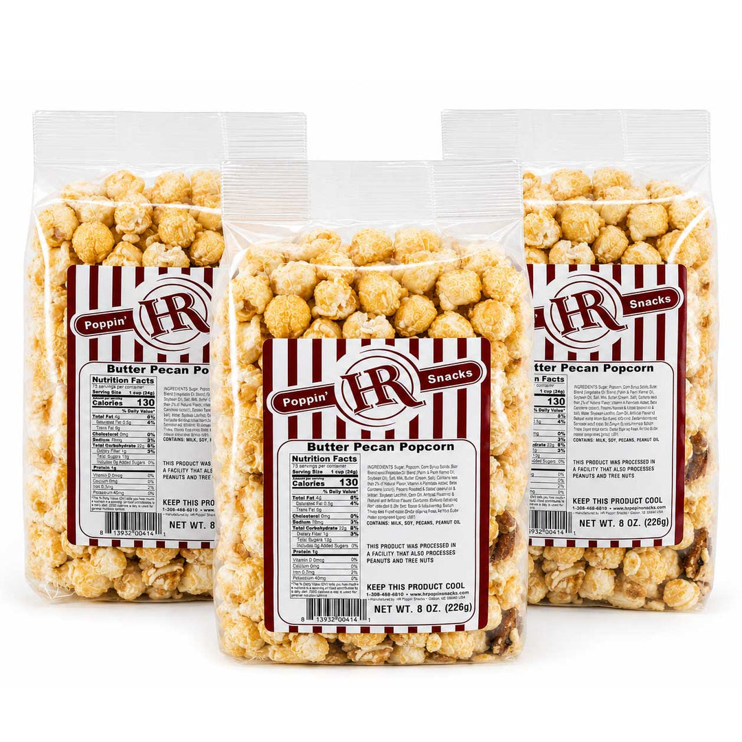 Three clear bags of Butter Pecan Popcorn with red and white striped labels, arranged in a fan shape on a white background.