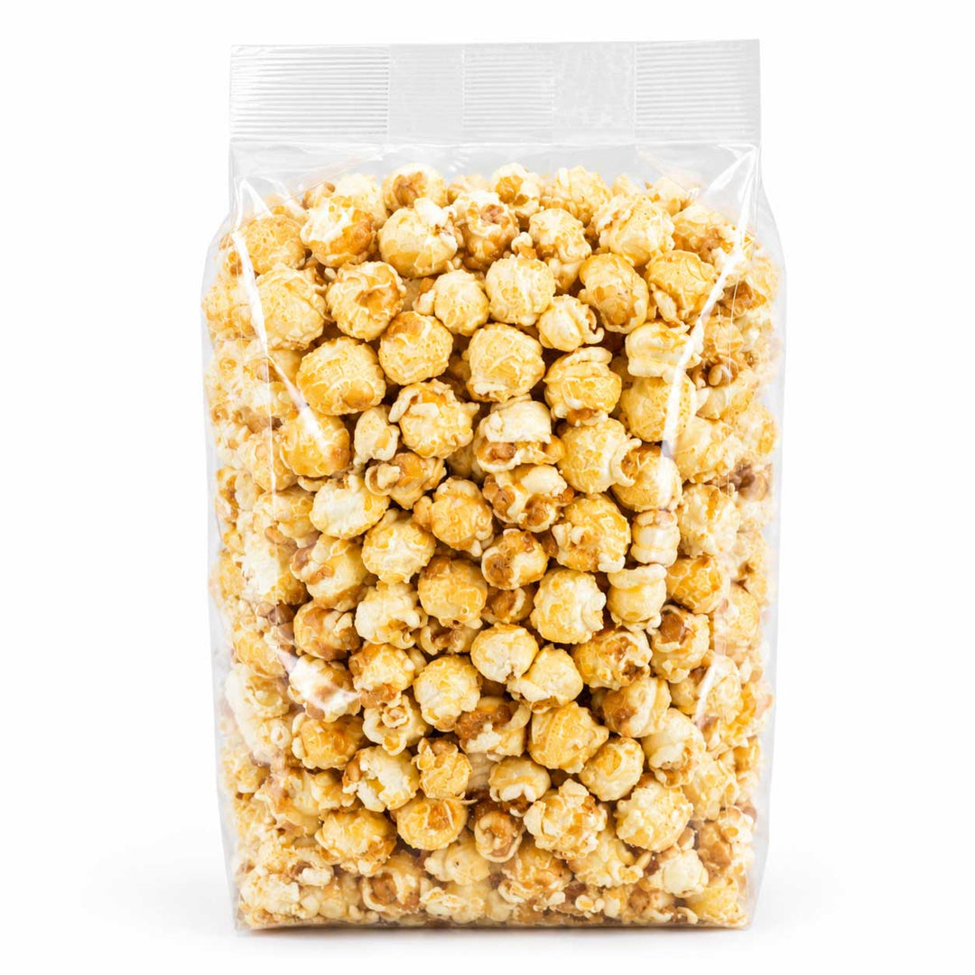 A clear plastic resealable bag filled with caramel popcorn on a plain white background.