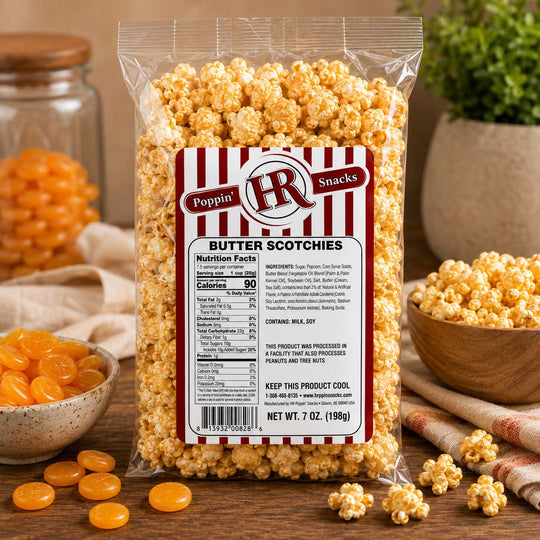 A 7 oz bag of Poppin' HR Butter Scotchies popcorn on a wooden table, surrounded by bowls of caramel candies and additional popcorn, with a warm, cozy background.