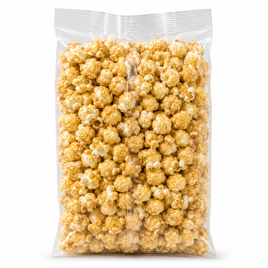 A clear plastic bag filled with caramel popcorn on a plain white background.