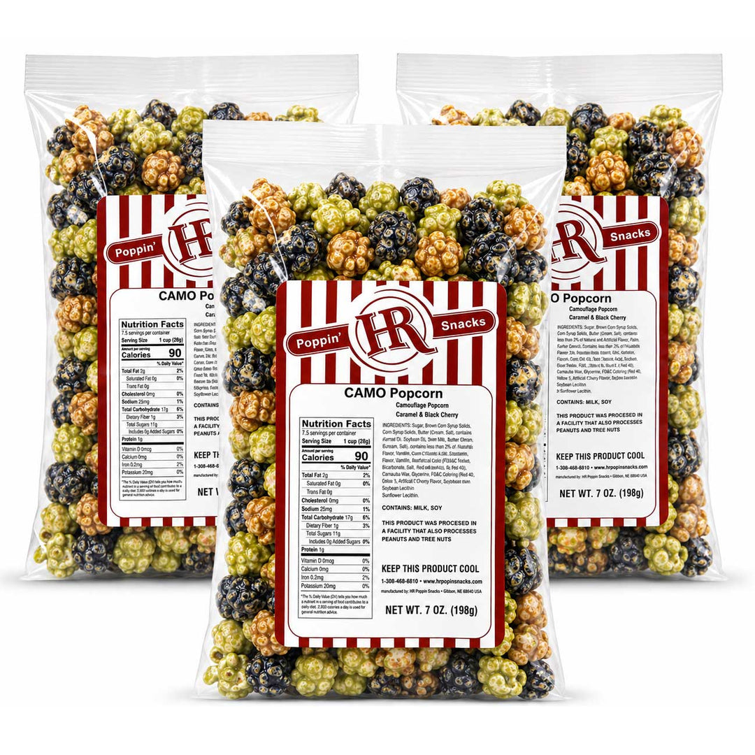 Three clear plastic bags of Poppin' Brunches CAMO Popcorn arranged in a fan shape on a white background. The bags contain a mix of red, black, and green popcorn kernels, and each bag has a white label with red and black branding.