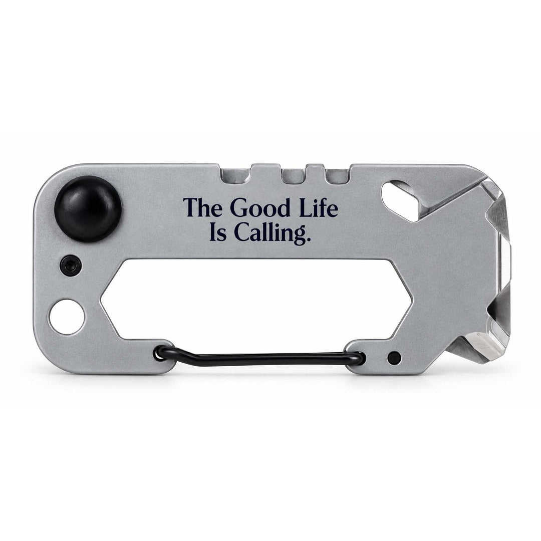 A silver multi-tool card with black accents, featuring the engraved text 'The Good Life Is Calling.' and a black carabiner clip, shown on a white background.