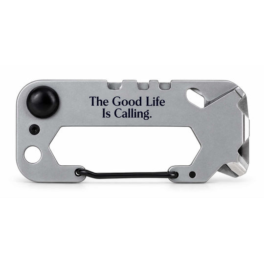 A silver multi-tool card with black accents, featuring the engraved text 'The Good Life Is Calling.' and a black carabiner clip, shown on a white background.