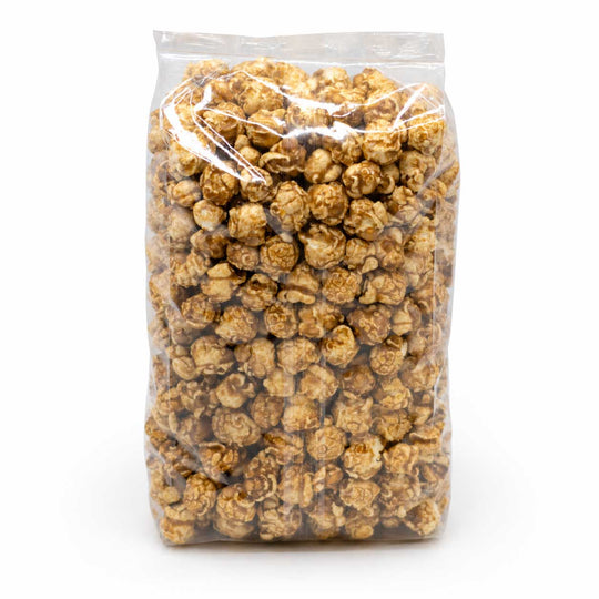 A clear plastic bag filled with caramel popcorn on a plain white background.