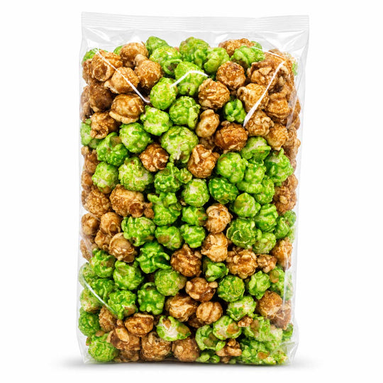 A clear plastic bag filled with mixed popcorn, featuring bright green coated popcorn and brown uncoated popcorn, set against a plain white background.