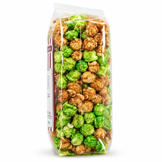A clear plastic bag filled with mixed caramel popcorn, including green-coated and plain brown popcorn, shown on a white background.