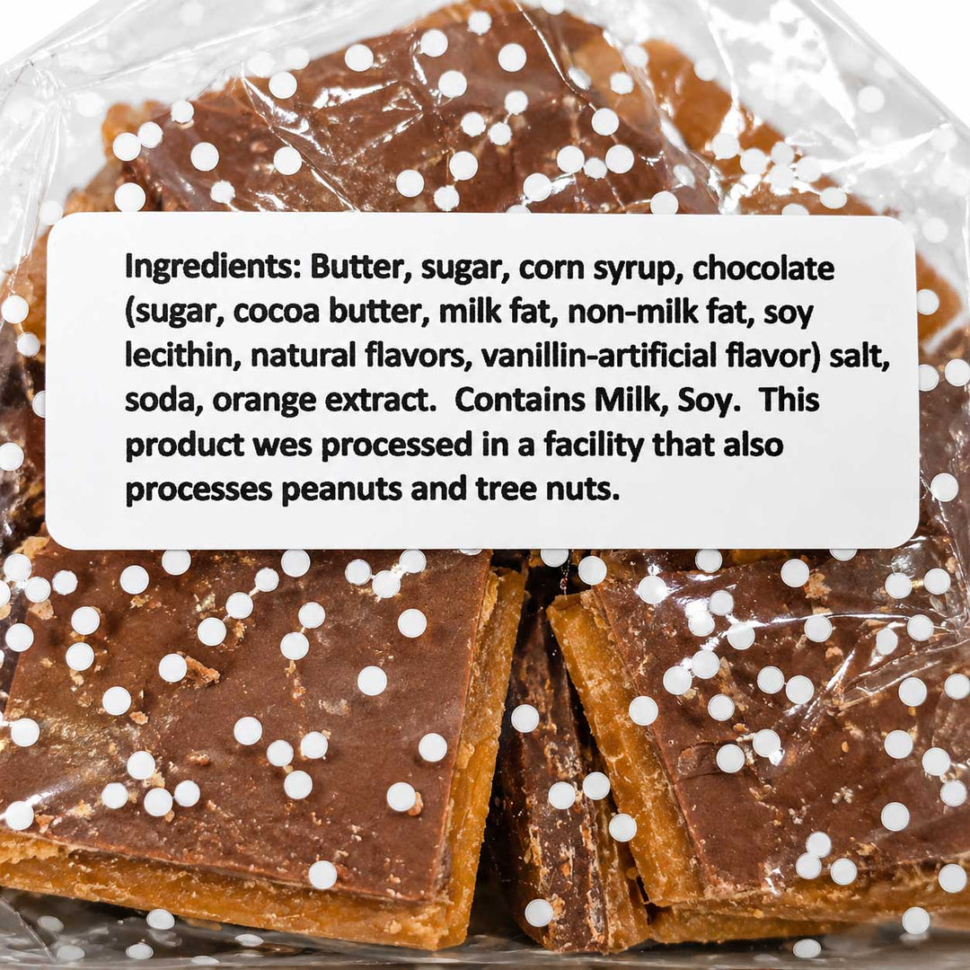 Chocolate-covered square candies or fudge pieces wrapped in clear plastic, with a white label showing ingredients and a nut allergy warning.
