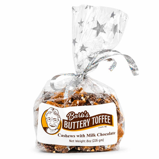 A 8 oz bag of Bar's Buttery Toffee cashews with milk chocolate, wrapped in clear cellophane with a silver star-patterned bow and tied with a silver ribbon. The product is displayed on a clean white background.