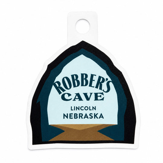A die-cut sticker featuring the logo for Robber's Cave Lincoln Nebraska, displayed on a clean white background.