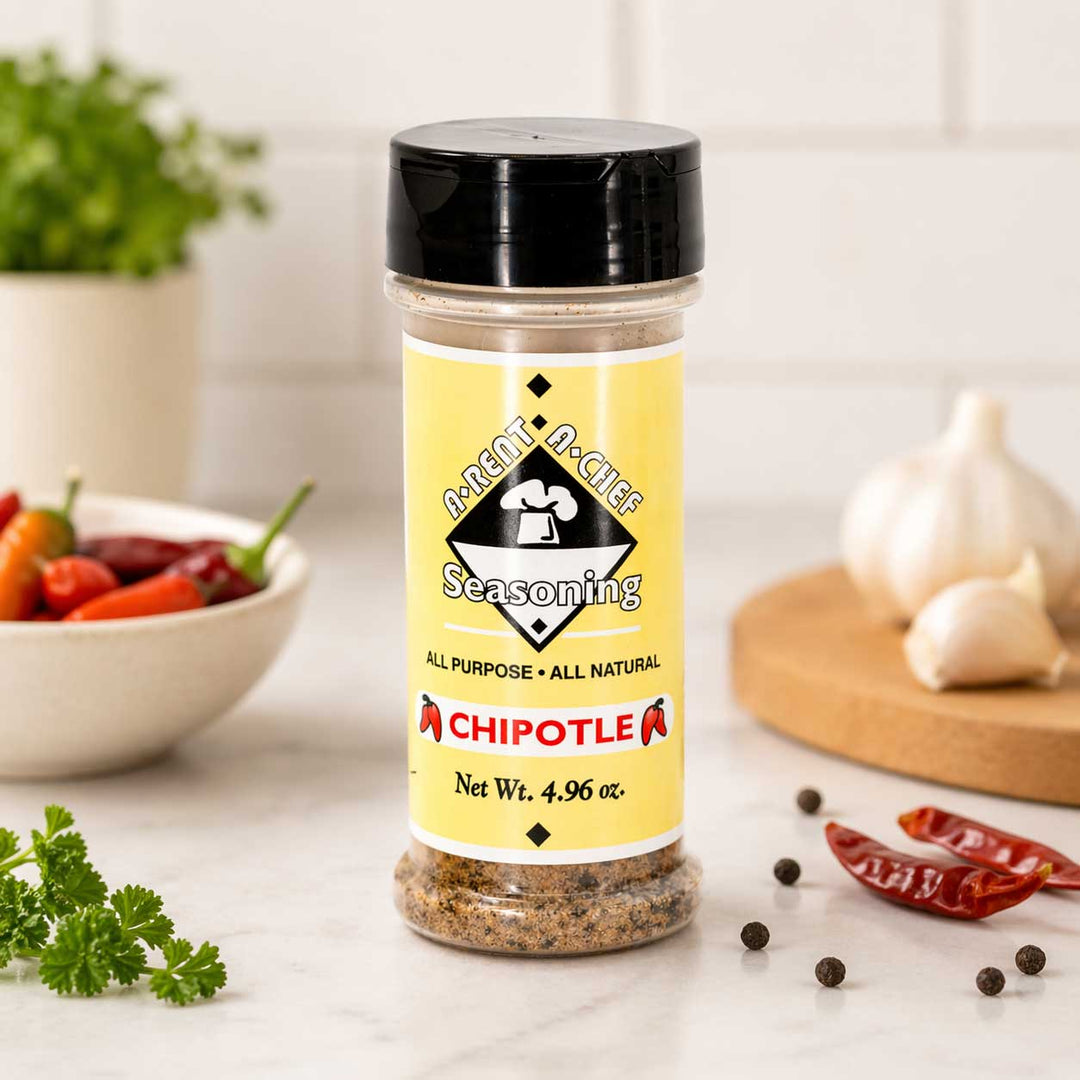 Bottle of A-Rent-A-Chef Chipotle seasoning on a kitchen counter with vegetables in the background.