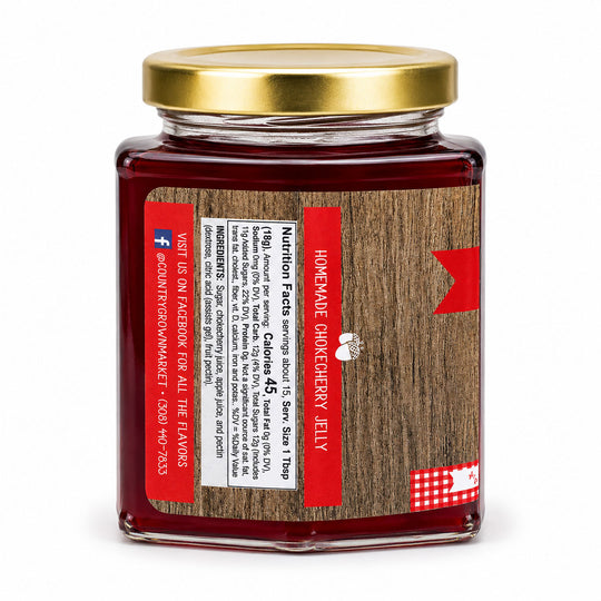 Jar of homemade cranberry cherry jelly with a gold lid on a white background