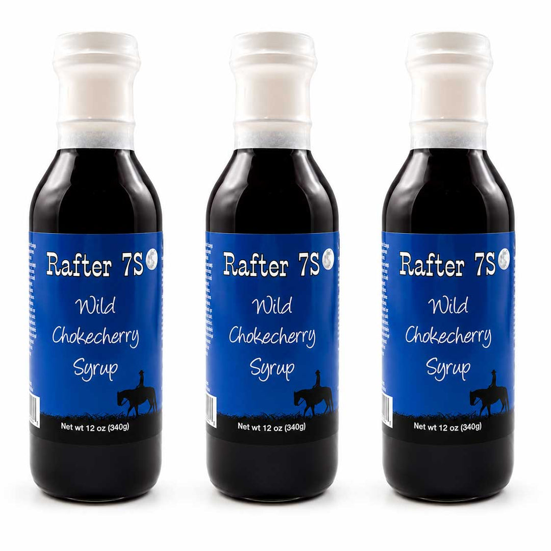 Three bottles of Rafter 7S Wild Chokecherry Syrup on a white background