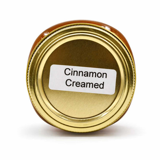 Gold jar lid with 'Cinnamon Creamed' label on a white background