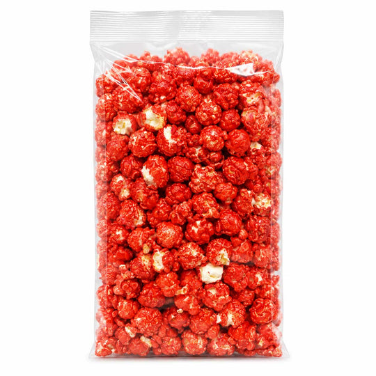 A clear plastic bag filled with bright red popcorn on a plain white background.