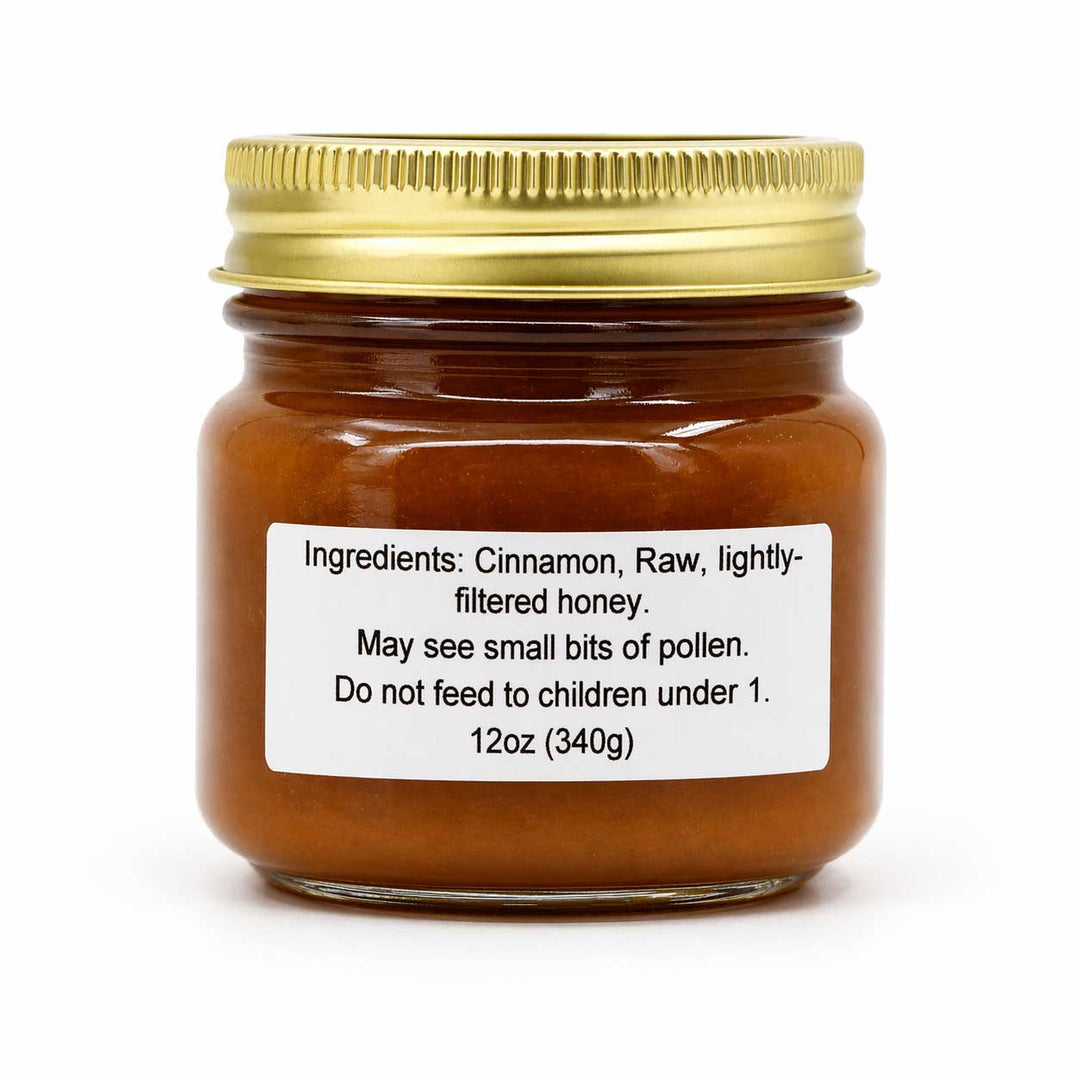 Jar of cinnamon honey with a gold lid on a white background