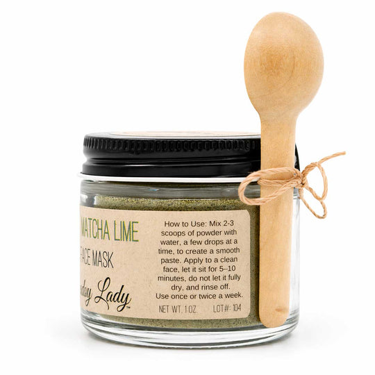 Jar of matcha lime face mask with a wooden spoon on a white background