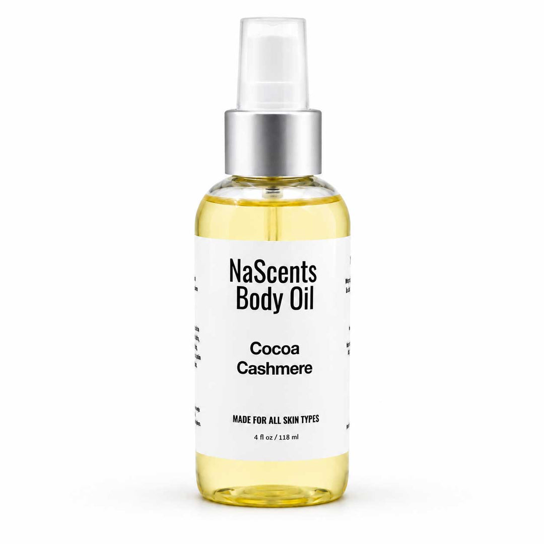 A bottle of NaScents Body Oil in the Cocoa Cashmere scent, featuring a clear bottle filled with pale yellow oil, a white label with black text, and a silver pump dispenser, set against a plain white background.