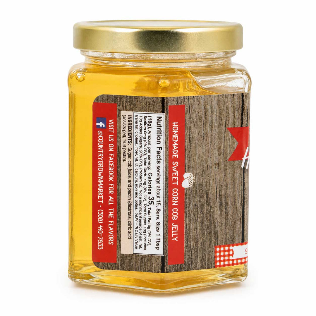 Jar of homemade sweet corn cob jelly with a gold lid on a white background