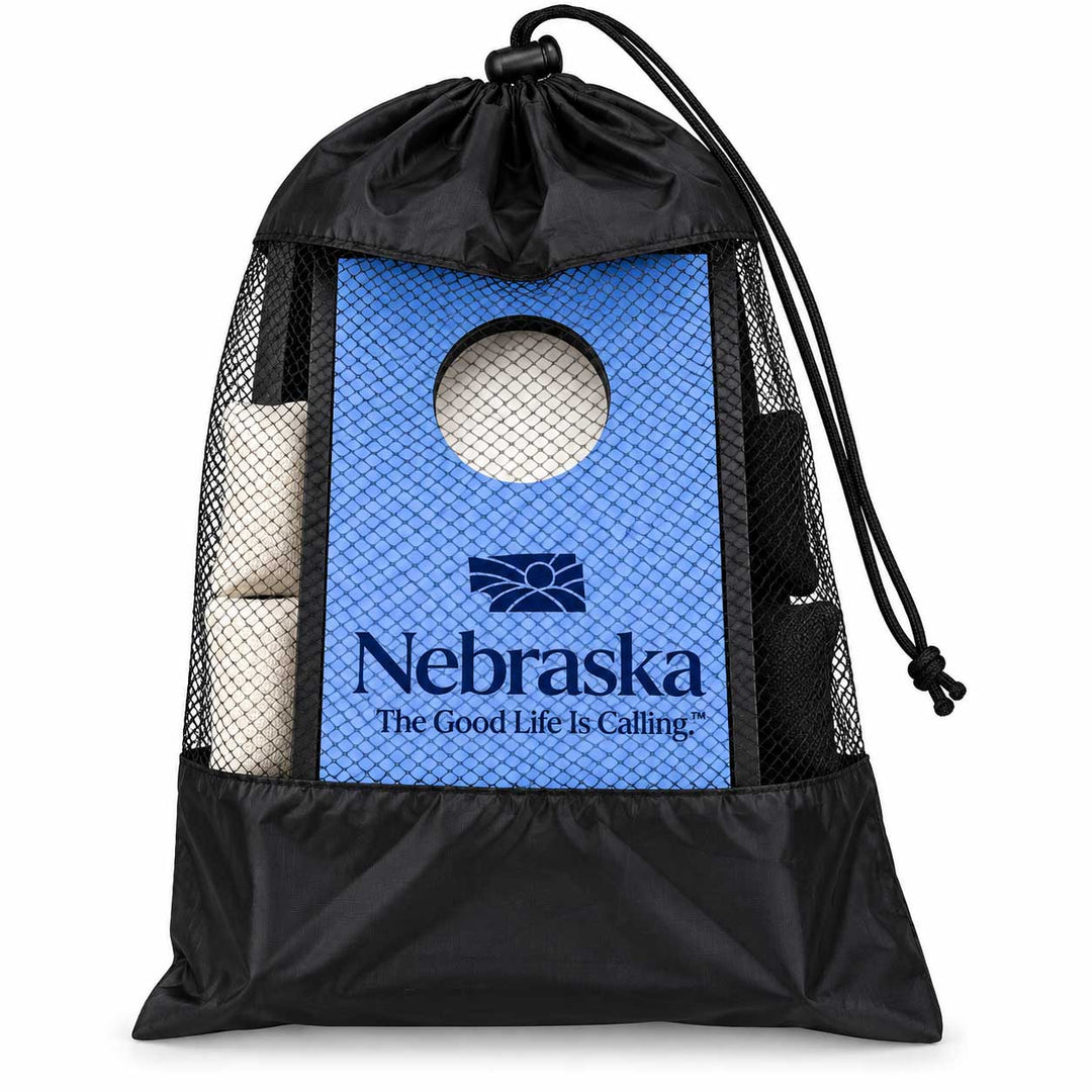 A black drawstring storage bag with mesh sides, featuring a blue Nebraska Cornhuskers themed insert panel with a circular cutout and rolled white corn in the side pockets, shown on a white background.