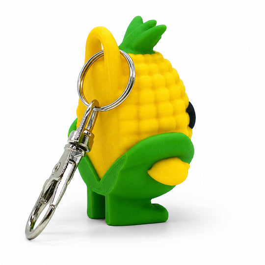 A novelty keychain shaped like a corn cob, featuring a yellow textured body, green top and lower wrapper, a silver split ring, and a silver lobster clasp on a white background.
