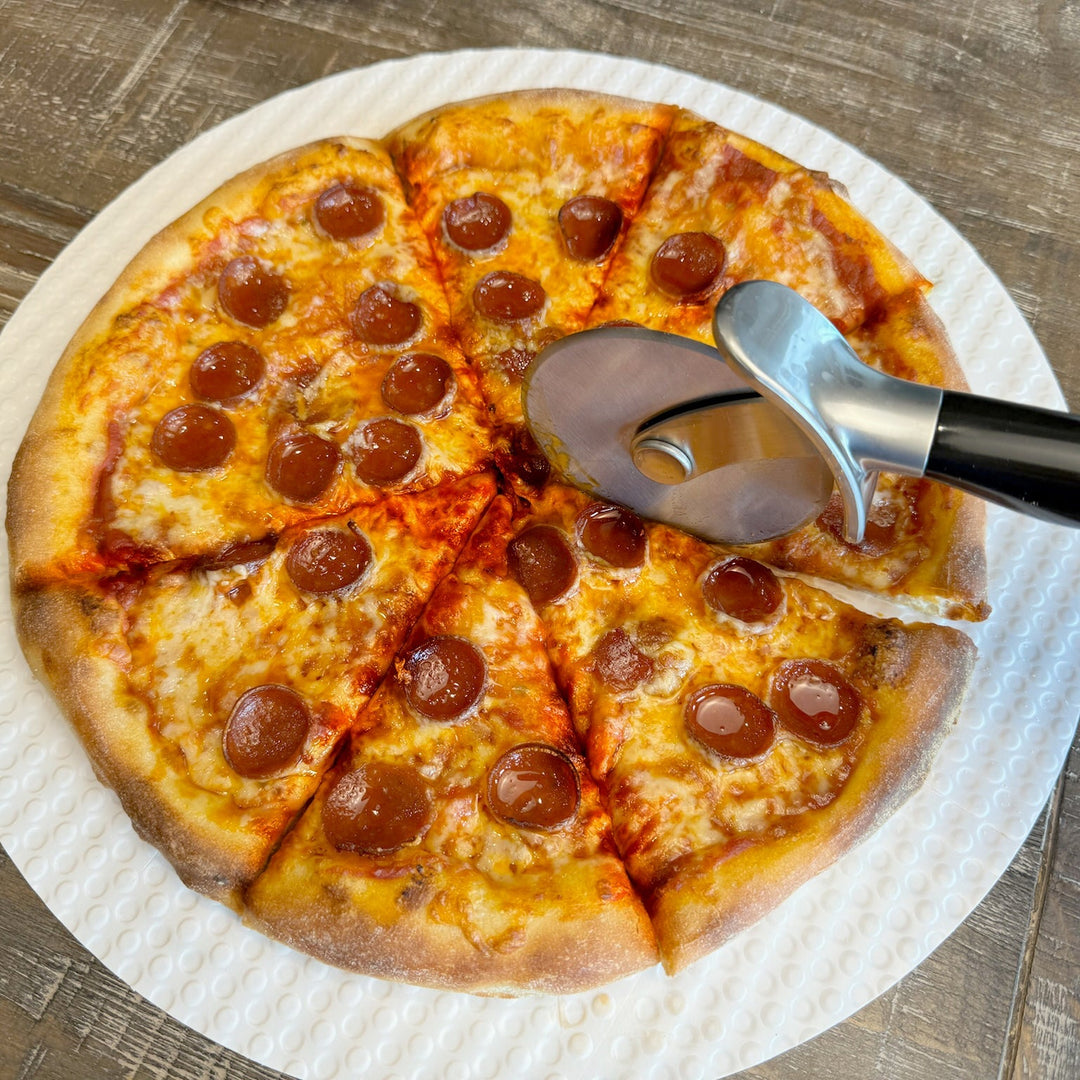 Pepperoni pizza on a paper plate with a pizza cutter