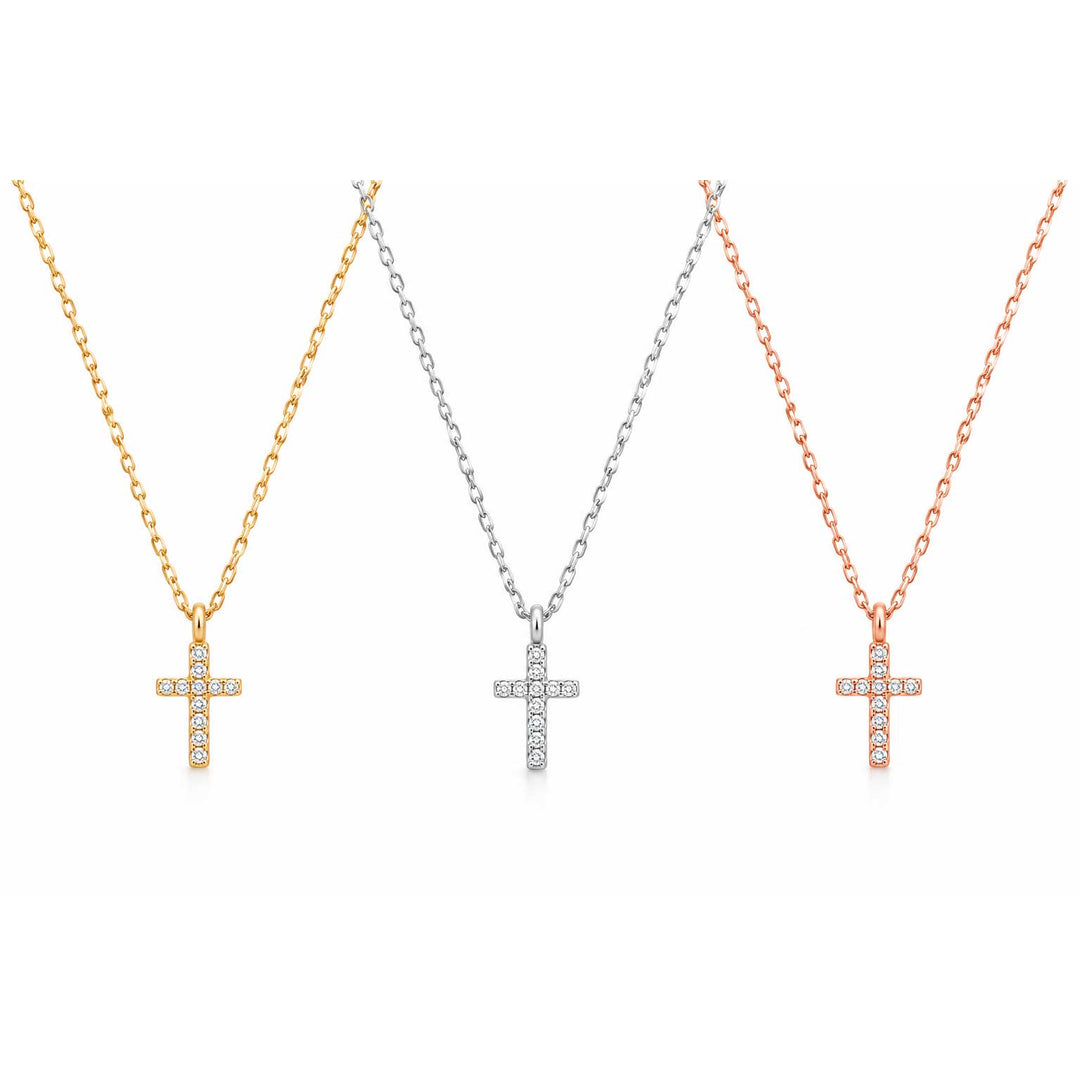 Three cross pendant necklaces on chains, shown side by side in yellow gold, silver, and rose gold tones. Each cross is adorned with small clear stones, set against a plain white background.