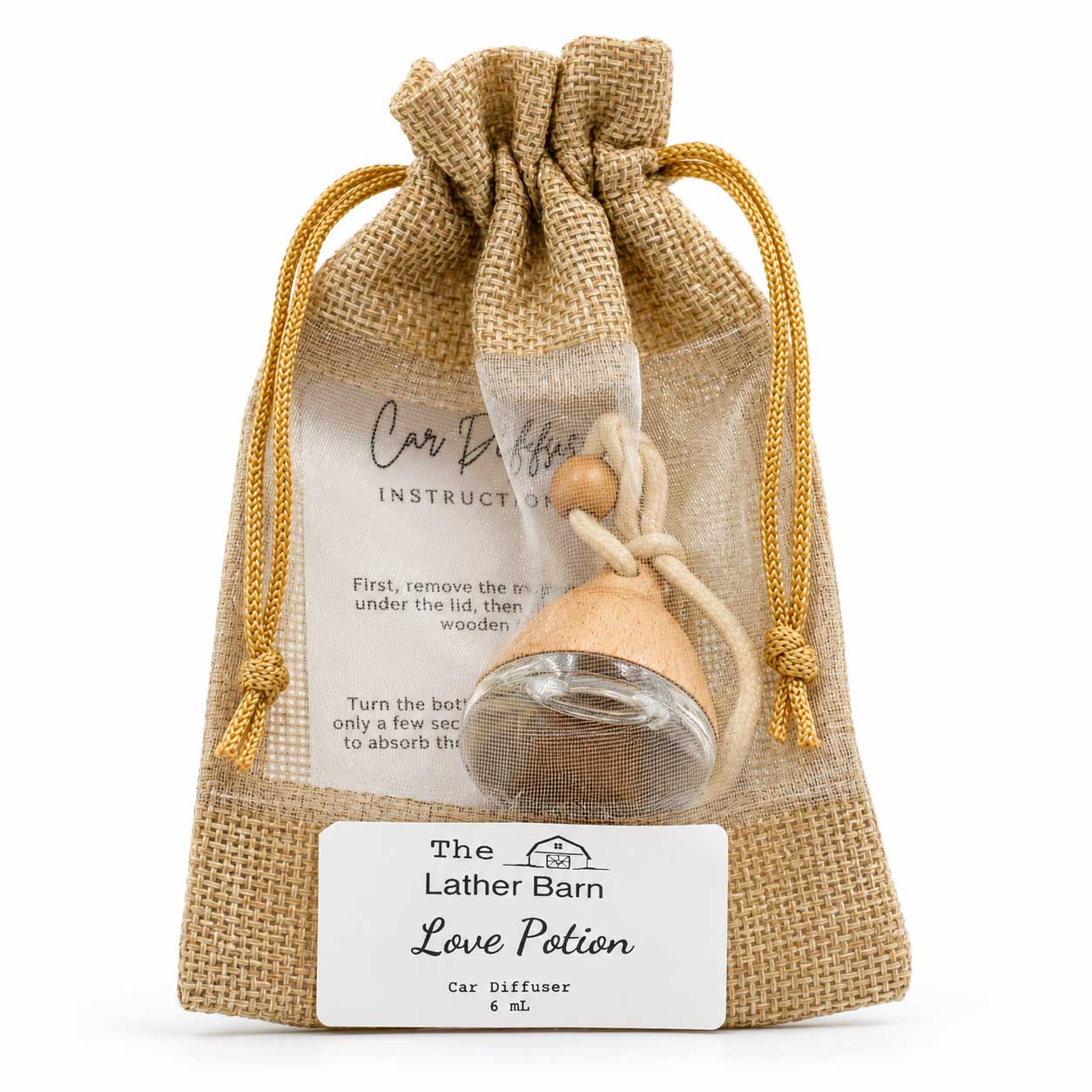A car diffuser gift set in a natural burlap drawstring pouch, featuring a small wooden and glass car diffuser labeled 'The Lather Barn Love Potion' with an instruction card inside.