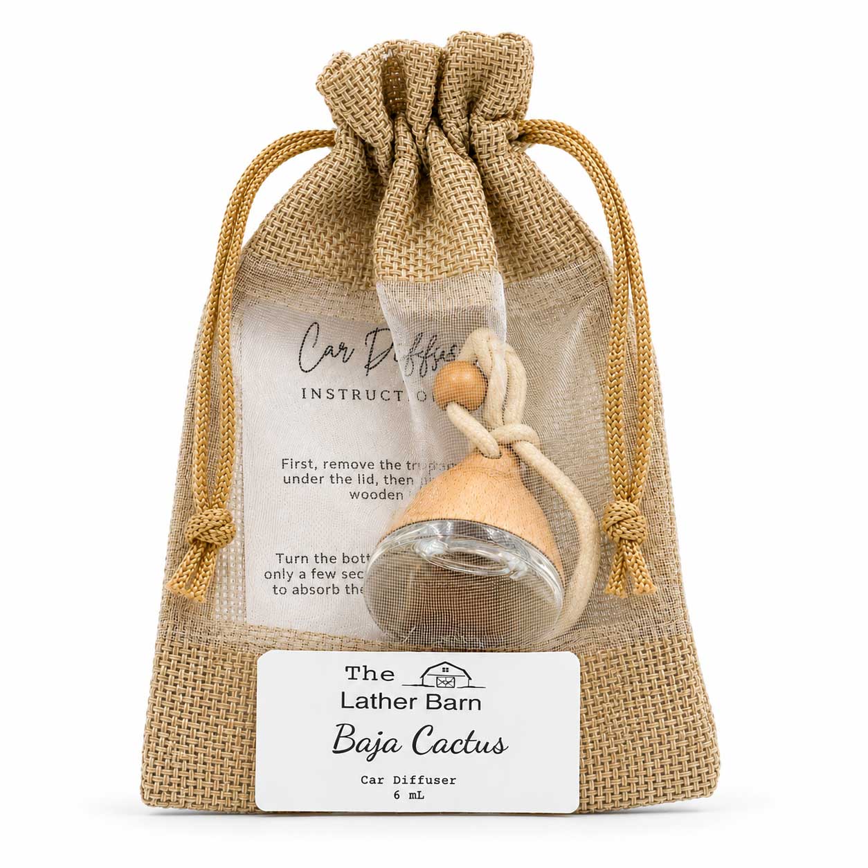 A car diffuser set in a clear drawstring burlap pouch with a white instruction card and a white brand label. The diffuser has a clear glass bottle, a light natural wood diffuser top, and a beige cord.